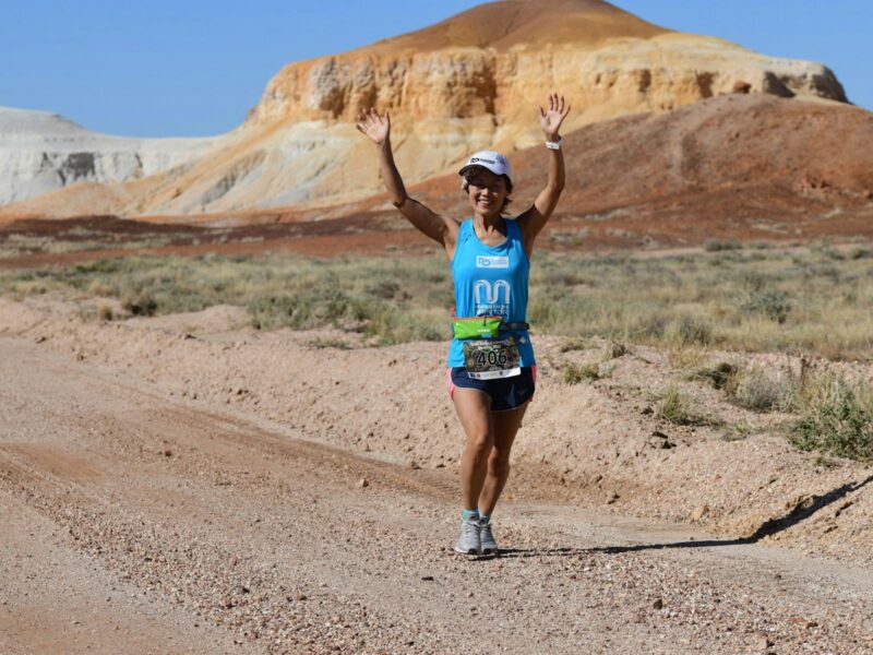 single runner in front of Papa Kutjara coloured hills in Kanku-Breakaways