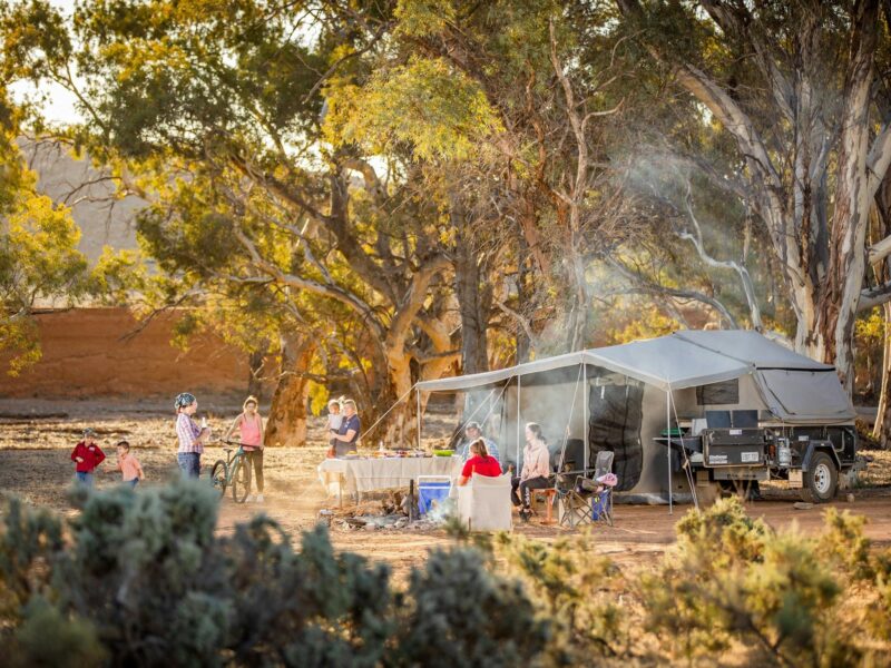 Sitting by campfire at Bluff View campsite with camper trailer.