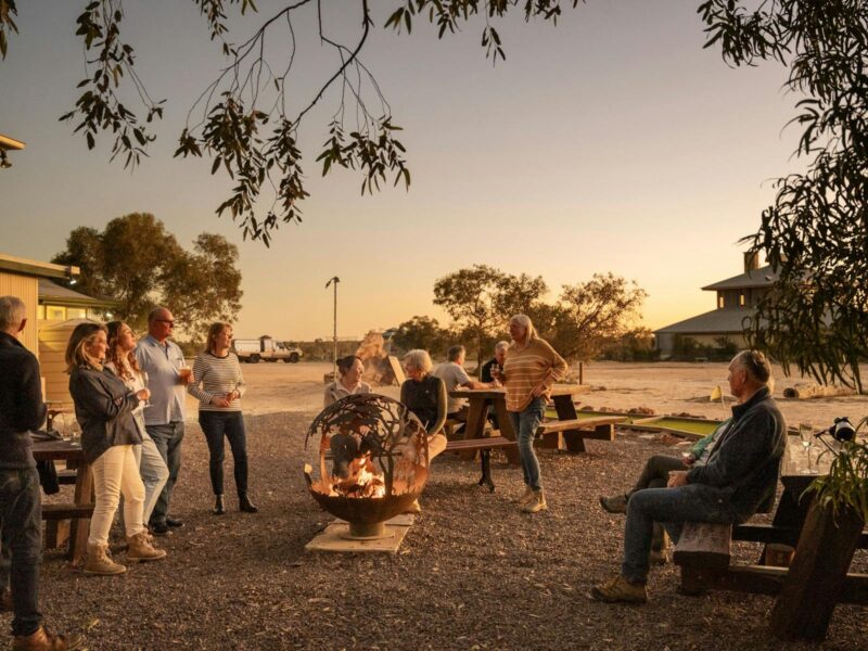 A group of patrons are socialising in the hotel's outdoor area at twilight.