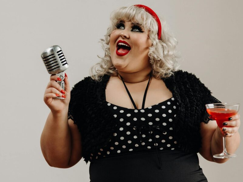 ATDW-Beating-up-the-Beatles-Port-Pirie.jpeg A photo of a singer holding a microphone in one hand, and a red drink in the other.