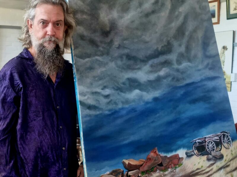 ATDW Gulnare Gallery And T Stop.jpeg Resident artist John Blackwell standing beside his painting 'Yacka Storm'