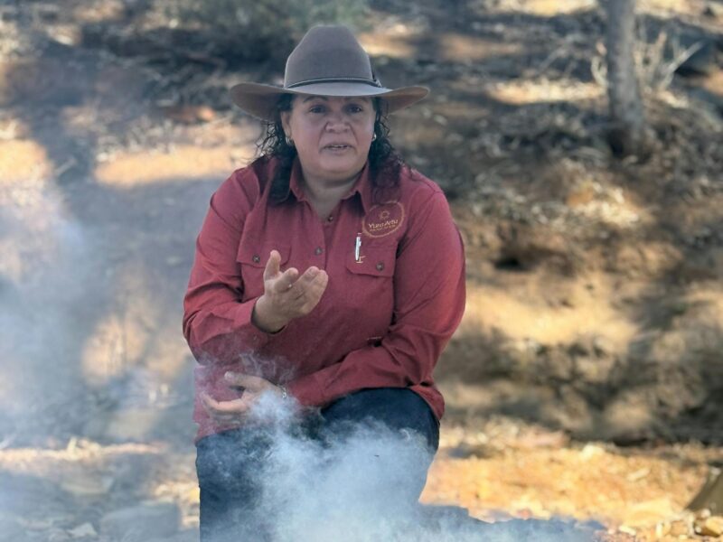 Sitting in a creek bed; in front of a smoking ceremony