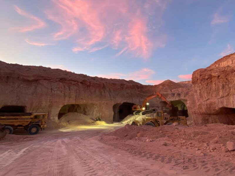 Open-cut opal mine with machinery under a pink sunset sky